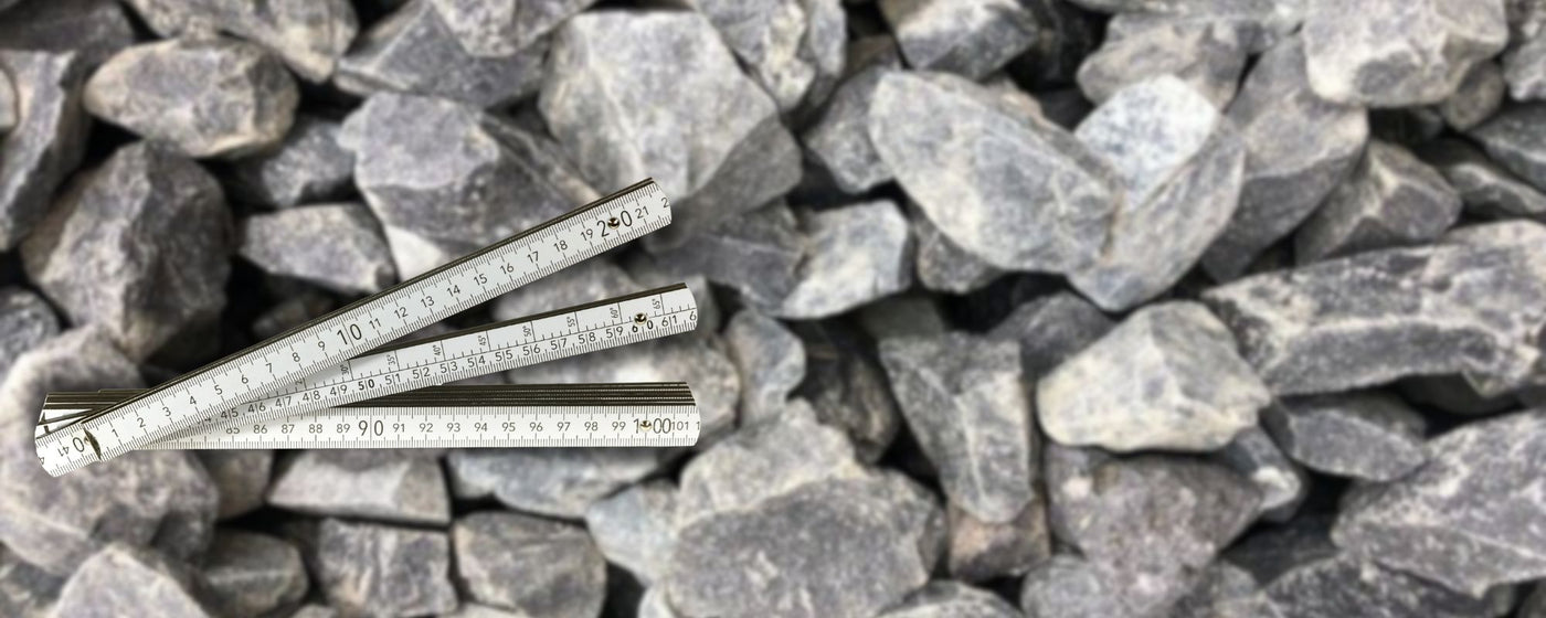 Grauer Splitt wird ausgesiebt – Nahaufnahme von grauem Ziersplitt in mittlerer Körnung, der durch ein Sieb fällt, Symbolbild für Steingröße und Korngröße beim Kies.